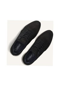 Zwarte sneakers met een soepel suède bovenwerk, ronde neus, platte witte rubberen zool en zwarte veters. Het "Greve" logo is zichtbaar aan de binnenkant.