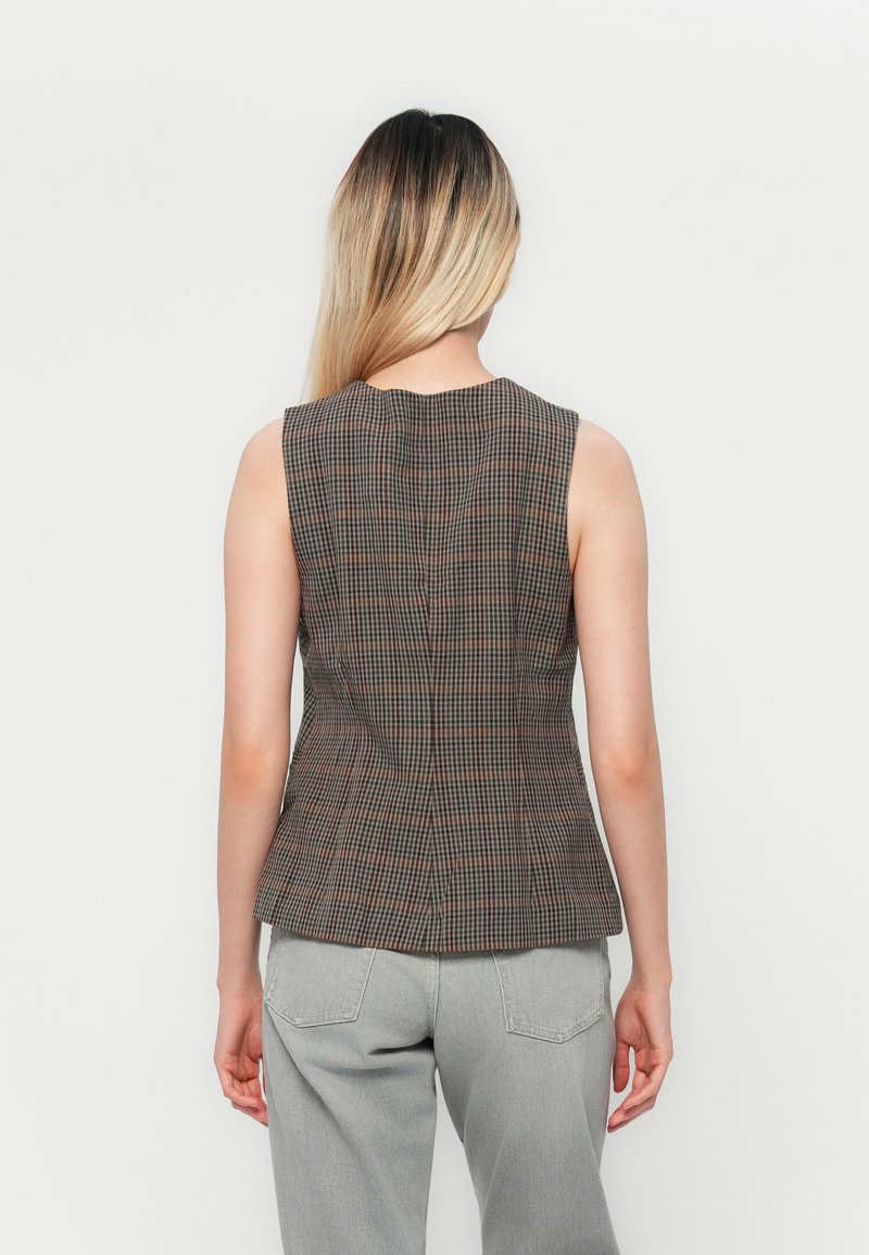 Braun karierter ärmelloser Weste mit taillierter Passform, runder Ausschnitt und Peplum-Silhouette. Kombiniert mit grauen Hosen.