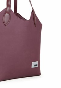 Burgundy tote bag lavet af tekstureret stof med glatte læderdetaljer. Har et lille rektangulært logo på siden.