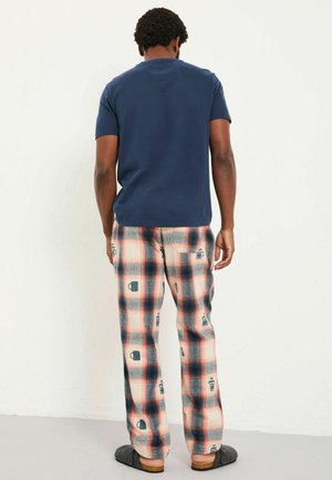 Navyblaue Baumwoll-T-Shirt kombiniert mit karierter Flanellhose in Creme, Rot und Navy, mit Mustern aus Kaffeetasse und French Press.