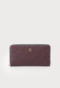 Red and navy patterned wallet with a textured exterior, featuring a gold logo accent. Secured by a zip closure along the sides.