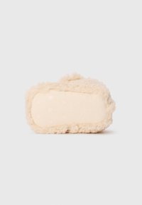 Beige, fluffy tøfler med en teksturert, myk overflate. Sålen har en tan gummibunn med forhøyede solstrålemønstre og merkevarelogo.