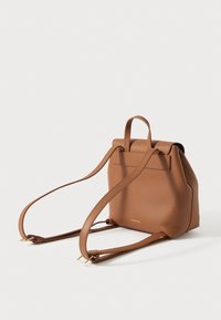 Καφέ δερμάτινο σακίδιο με δομημένο σχήμα, δύο ρυθμιζόμενους ιμάντες και λαβή στο πάνω μέρος. Διαθέτει υφή φινιρίσματος και ελάχιστη σήμανση.