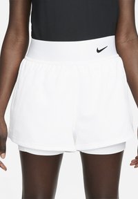 White athletic shorts with a wide elastic waistband and layered design. Features a small black Nike logo on the front waistband.