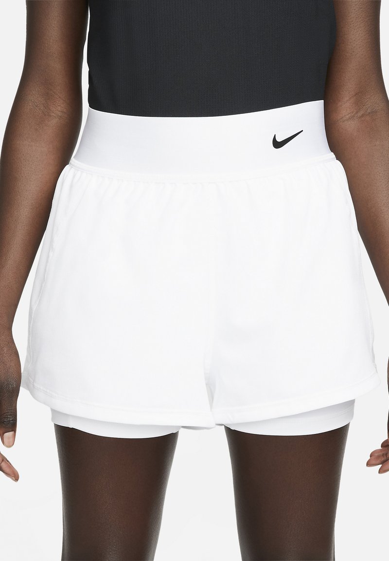White athletic shorts with a wide elastic waistband and layered design. Features a small black Nike logo on the front waistband.
