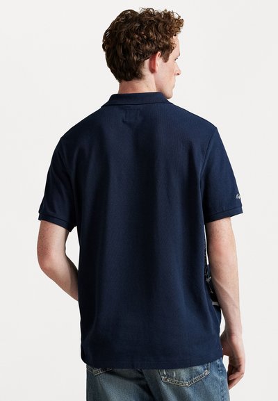 Μπλε ναυτικού πόλο μπλουζάκι με κοντά μανίκια, φτιαγμένο από υφασμένο βαμβάκι. Διαθέτει απλή σχεδίαση και ριμπ κολάρο.