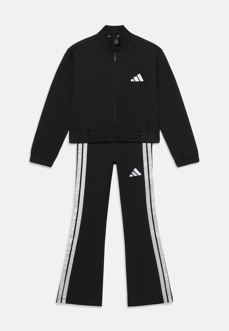 Chándal negro que incluye una chaqueta con cremallera y pantalones acampanados. Rayas plateadas a los lados y un pequeño logo en la chaqueta y la cinturilla.