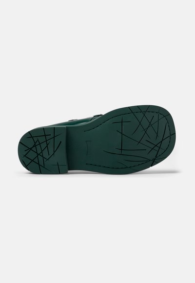 Green rubber shoe sole with deep tread patterns; textured surface; curved shape at the toe; reinforced heel for durability.