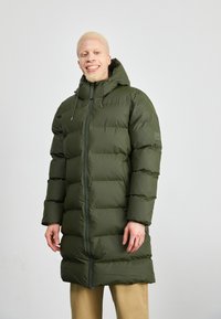 Žalias pūkuotas paltas su gobtuvu, turintis horizontalias siūles, priekinį užtrauktuką ir elastingas raištelius ant kaklo.