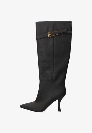 Botte noire montant en cuir texturé avec un motif crocodile. Présente un bout pointu et un talon aiguille élancé. Accent avec une boucle dorée.