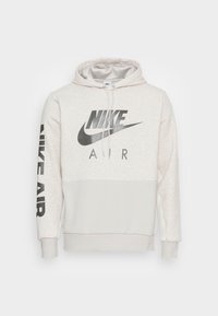 Svěle šedá mikina Nike s kapucí podšitou síťovinou, s černými logy na hrudi a rukávu, s elastickými manžetami a spodním lemem a měkkou texturou.