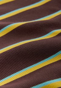 Brunt ribbet stof med vandrette gule og lyseblå striber, der viser tekstur og bløde folder i materialet.