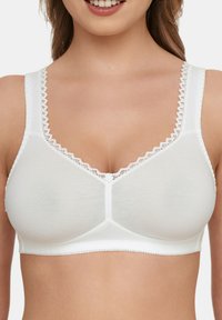 Weißer wireless BH mit glatter Textur, V-Ausschnitt-Design, dekorativem gewellten Saum an den Trägern und einem floralen Akzent in der Mitte vorne.