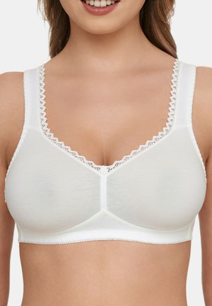 Weißer wireless BH mit glatter Textur, V-Ausschnitt-Design, dekorativem gewellten Saum an den Trägern und einem floralen Akzent in der Mitte vorne.