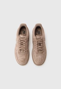 Baskets Nike Air en daim marron clair, avec des lacets ronds, une boîte à orteils perforée, un col rembourré et un logo embossé sur la languette.