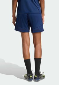 Μπλε ναυτικό αθλητικό σορτς από ελαφρύ ύφασμα, με άνετη εφαρμογή, λεπτομέρειες από δίχτυ και ελαφριά γυαλάδα, συνδυασμένα με μαύρες κάλτσες συμπίεσης.