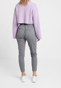 Lila kort tröja med ribbad textur, kombinerad med grå tapered joggers som har resårmidja. Stylad med vita träningsskor.