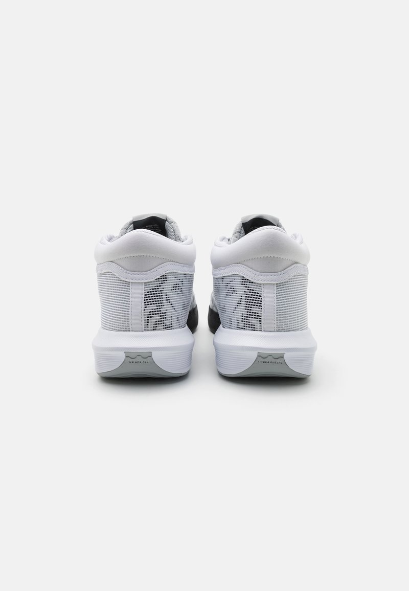 Zapatillas deportivas en blanco y negro con una parte superior de malla, cuello acolchado y suela de goma texturizada, que cuentan con tonalidades duales y detalles de marca mínimos.