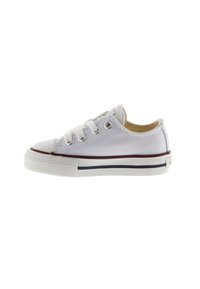 Zapatilla baja de lona blanca con punta redonda, rayas rojas y azules contrastantes en la suela, y tres ojetes para los cordones.