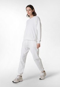 Vit sweatshirt och joggers i mjukt material, med avslappnad passform, ribbade manschetter och sidodetaljer. Matchat med beige sneakers.