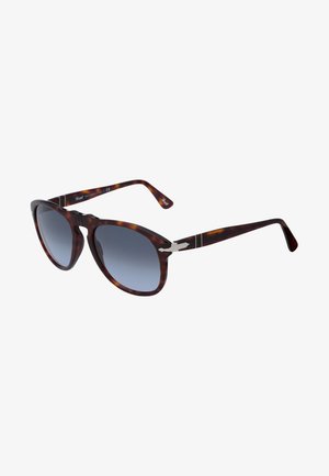 Óculos de sol em padrão tartaruga castanho com lentes degradê, formato arredondado, detalhes em metal nas hastes e padrões subtis.