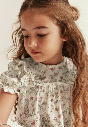 Weißes Kleid mit floralem Muster, das Kaninchen und Rehe zeigt. Rüschensleeves, weiches Baumwollmaterial und ein gewellter Ausschnitt.