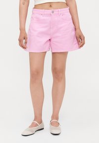 Bermudas de mezclilla a rayas rosas y blancas con una cintura de altura media, bolsillos frontales y detalles de metal plateado en la cinta del cinturón.