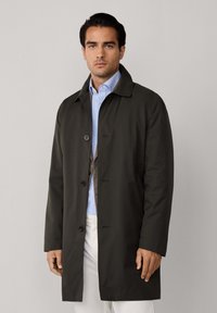 Tummanvihreä, vettähylkivä takki, jossa on kauluspanta, yksinkertaiset napit ja sileä pinta, kerros vaaleans蓝 בלאו. 