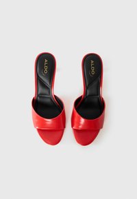 Red leather slide sandals with a wide upper band and open toe. Black insole with gold "ALDO" branding. Smooth texture and minimalist design.