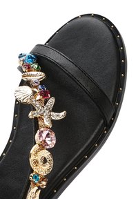 Sandalo scivoloso nero con suola piatta, adornato con hardware in tonalità d'oro e dettagli in pietre preziose multicolori ispirati al tema marino.