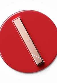 Compact cosmétique circulaire rouge avec une finition brillante, doté d'une fermeture rectangulaire couleur or avec un détail de bord angulaire.