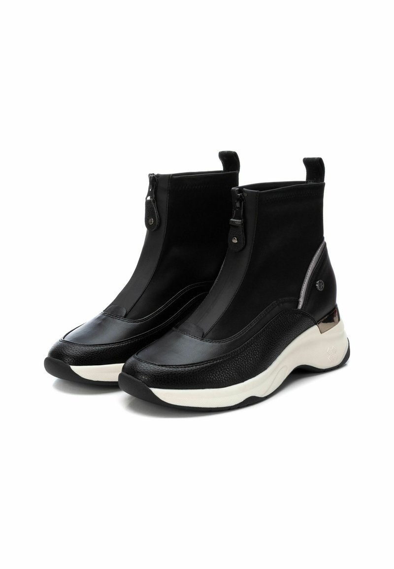 Bottines noires avec un design épuré, dotées d'un dessus en cuir lisse, d'accents texturés et d'une semelle blanche rembourrée. Détail de fermeture éclair à l'avant.