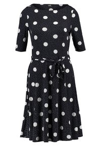 Marinblå klänning med vita prickar och mindre mönster. Har rund nacke, korta ärmar och en knut i midjan för justerbar passform.