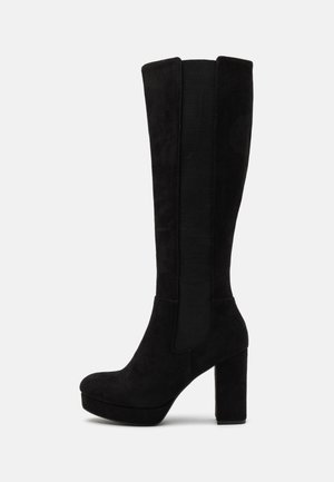 Bottes noires en nubuck jusqu'au genou avec un talon épais, dotées de panneaux élastiques sur les côtés pour l'étirement et d'un design à bout arrondi.