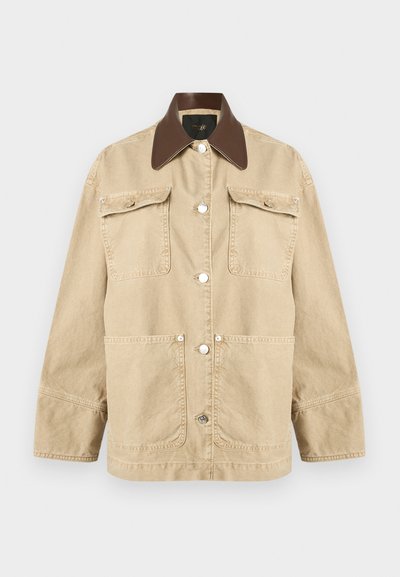 Veste beige à manches longues avec col pointu marron foncé, quatre poches avant et fermetures à boutons-pression argentés au centre.