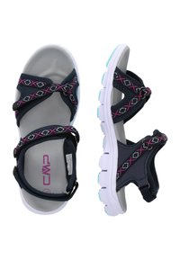 Tummansinisiä sandaaleja, joissa on vaaleanpunaiset ja valkoiset kuvioidut hihnat, pehmeällä pohjalla ja kontrastivalkoisella kumipohjalla.