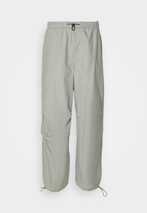 Lichtgrijze, lichte broeken met een elastische tailleband, verstelbaar trekkoord en zijzakken. Kenmerkt zich door een relaxte fit en taps toelopende boorden.