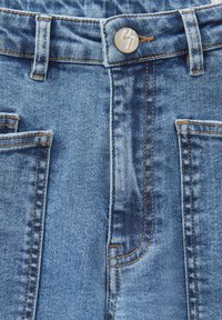 Jeans in denim di colore azzurro chiaro con una finitura testurizzata. Le caratteristiche includono un bottone metallico, tasche rinforzate e dettagli di cucitura visibili.