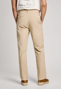 Pantaloni di cotone beige, design a gamba dritta, con tasche posteriori. Abbinati a scarpe slip-on marroni, tessuto testurizzato, stile casual.