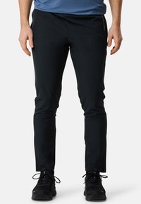 Zwarte stretchbroeken met een slim fit ontwerp, een gladde textuur en discrete branding aan de linkerkant. Verstelbare manchetten en lichtgewicht stof.