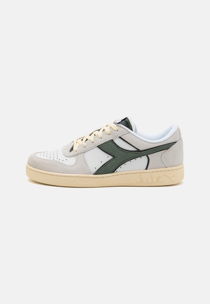 Hvit og grå sneaker med grønne aksenter, i semsket skinn og lærmaterialer, perforert tå, flat beige såle og en logo på siden.