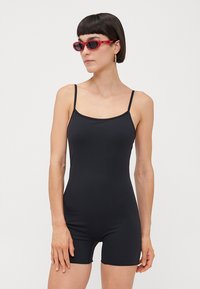 Black sleeveless bodysuit made of stretchy material, featuring a rounded neckline and fitted design, complemented by thin shoulder straps.