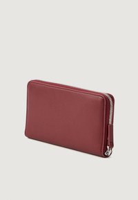 Cartera de cuero marrón con un acabado texturizado, que presenta un zipper plateado a lo largo del borde superior y un tirador de zipper para un fácil acceso.