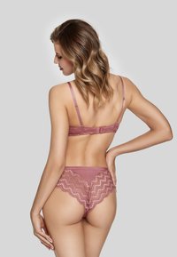 Lingerie set in soft rose color featuring triangular lace accents, adjustable straps, and scalloped edges on the back of the briefs.