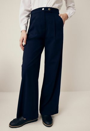 Jūriniai plačios kojų kelnės su aukštu liemeniu, turinčios dvi priekines kišenes, audinio raukšles ir sagos detalę. Lygus audinys ir pritaikytas siluetas.