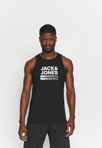 Débardeur noir sans manches avec le logo de la marque "JACK & JONES" et le texte "PERFORMANCE" en blanc. Tissu doux avec une texture lisse.