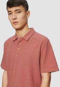 Polo met korte mouwen in een stofroze kleur, gemaakt van gestructureerd katoen, met een geknoopte halslijn en een klassieke kraag. Geen patronen of accenten.