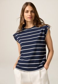 Top sin mangas de color azul marino con rayas horizontales blancas, con detalles de botones dorados en los hombros, confeccionado en una tela suave y con un corte relajado.