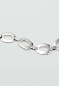 Silberne Metallarmband mit verlängerten ovalen Gliedern und abgerundeten Kanten, das eine glatte Oberfläche und eine einheitliche Textur aufweist.
