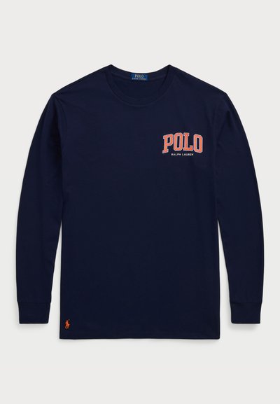 Jūrų kariuomenės ilgomis rankovėmis marškiniai, pagaminti iš medvilnės. Su "POLO" logotipu oranžine spalva, o po juo užrašas "RALPH LAUREN". Ant rankovės yra mažas oranžinis žirgo emblema.